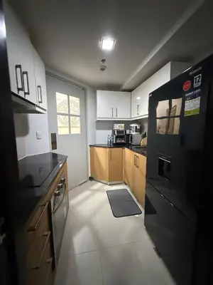 a kitchen with white cabinets and a black refrigerator at Cozy Apartment with Private Room in Vibrant Taguig in Manila