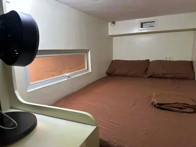 a small bedroom with a bed and a window at Cozy Loft Unit in Manila in Manila