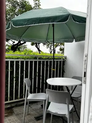 a table and chairs under a green umbrella on a balcony at Kasara T14K Cozy Abode in Manila
