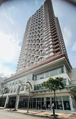a tall white building with a tree in front of it at Mandaluyong HomeBest Place to Stay! in Manila