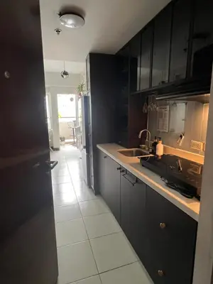 a kitchen with black cabinets and a white tile floor at Mandaluyong HomeBest Place to Stay! in Manila