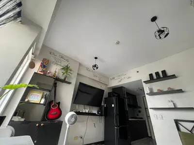 a kitchen with a refrigerator and a tv in a room at Mandaluyong HomeBest Place to Stay! in Manila