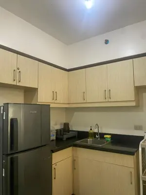 a kitchen with wooden cabinets and a stainless steel refrigerator at Resort Inspired Condo Beside NAIA Terminal 1 Near Okada and City of Dreams in Manila