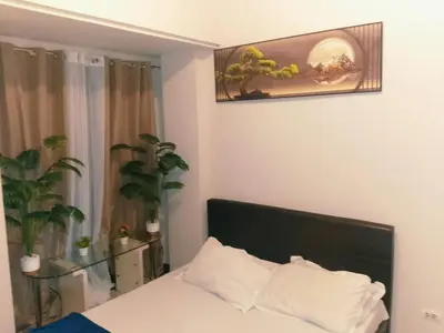 a bedroom with a bed with white sheets and a window at Condotels in Sucat Road in Manila