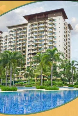 a large building with palm trees in front of a swimming pool at Condotels in Sucat Road in Manila