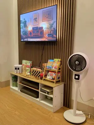 a room with a tv and a fan and a book shelf at The Azelea Suites By Azel in Manila