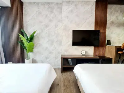 a hotel room with two beds and a television at Cozy MOA View Stay - Walk to Mall of Asia in Manila