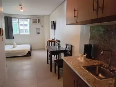 a room with a kitchen and a bedroom with a bed at Shandong Residences in Manila