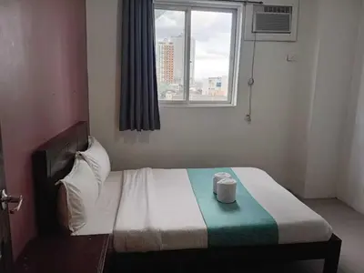 a hotel room with a bed with two cups on it at Shandong Residences in Manila