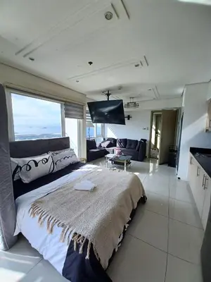a bedroom with a large bed and a living room at Your Home Near the Airport in Manila