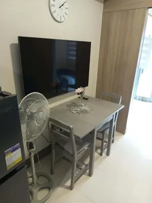 a dining room table with a fan and a clock at JCs Staycation Fame Residences in Manila