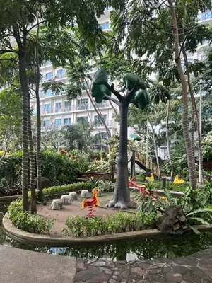a park with a tree in front of a building at Roomi Stays Acqua Private Residences in Manila