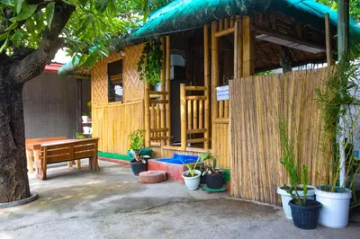a wooden house with a bench and potted plants at CLBC Bahay Kubo in Tagapo
