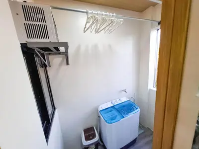 a room with a washing machine and a chandelier at CLBC Bahay Kubo in Tagapo