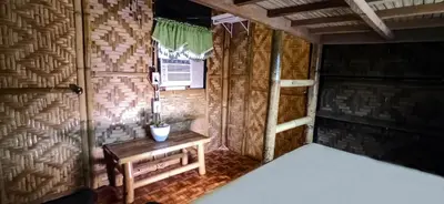 a room with a bed and a table in a room at CLBC Bahay Kubo in Tagapo