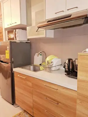 a kitchen counter with a sink and a refrigerator at Sunshine100 1Bedroom 65InchesTV PoolGymBilliardPlayground in Manila