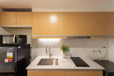 a kitchen with a sink and a black refrigerator at Luxury 1 BR City View in Park Mckinley West Fast Wi-Fi Washer Dryer in Manila