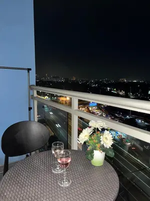 a table with wine glasses and flowers on a balcony at CozyCorner By R&K in Manila