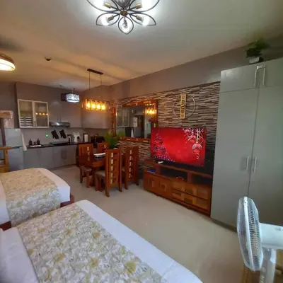 a room with two beds and a television and a dining room at The Morgan Residences in Manila