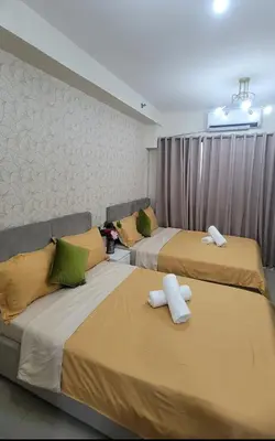 two beds in a hotel room with yellow and green pillows at Classy Stay in Manila