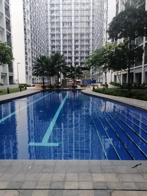 a blue swimming pool with tall buildings in the background at Classy Stay in Manila