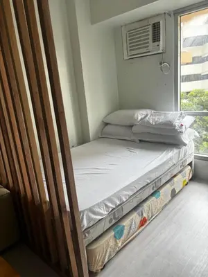 two beds in a room with a window at Ports Den in Manila