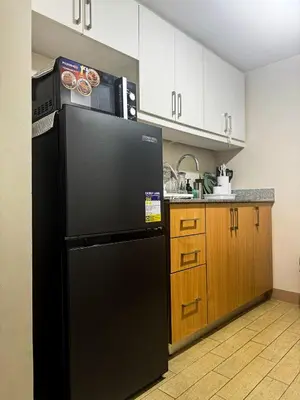 a black refrigerator with a microwave on top of it in a kitchen at Staycation in Manhattan near Smart Araneta in Manila