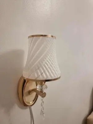a gold lamp with a white shade on a wall at 1569 Shore Residences MOA in Manila
