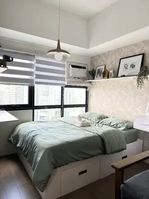 a bedroom with a large bed in a room with windows at Cozy Nature-Inspired Studio Unit in Cubao in Manila