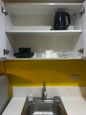 a kitchen with a sink and a shelf with dishes at Sunbeam - Lush Residence in Manila