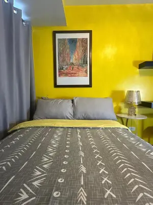 a bedroom with a bed with a yellow wall at Sunbeam - Air Residence 45th floor in Manila