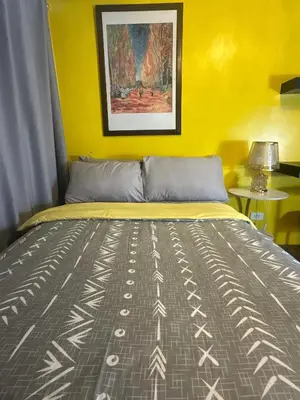 a bed in a room with a yellow wall at Sunbeam - Air Residence 45th floor in Manila