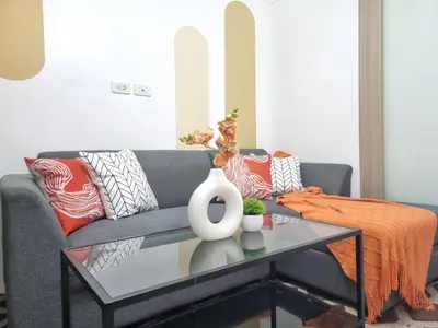 a living room with a gray couch with orange pillows at MP shore 1 c2 unit1583 in Manila