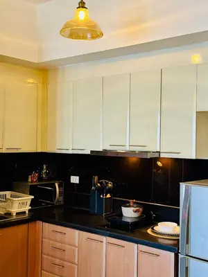 a kitchen with white cabinets and a black counter top at Cozy unit with balcony Netflix walk to Venice Mall in Manila