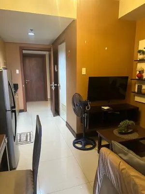 a living room with a couch and a table at Shell Residences Moa AJ in Manila