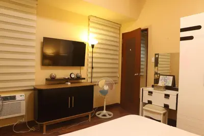 a bedroom with a television and a desk with a fan at The Mosaic Tower in Manila