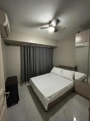 a bedroom with a bed and a ceiling fan at Condo near MOA Monarch in Manila