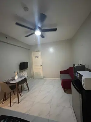 a living room with a ceiling fan and a couch at Condo near MOA Monarch in Manila