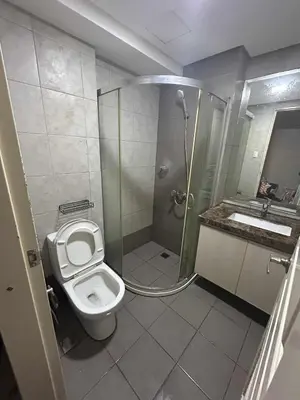 a bathroom with a shower and a toilet and a sink at Condo near MOA Monarch in Manila