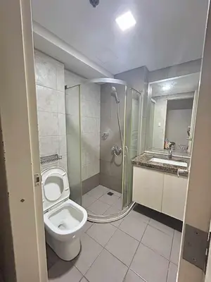 a bathroom with a shower and a toilet and a sink at Condo near MOA Monarch in Manila