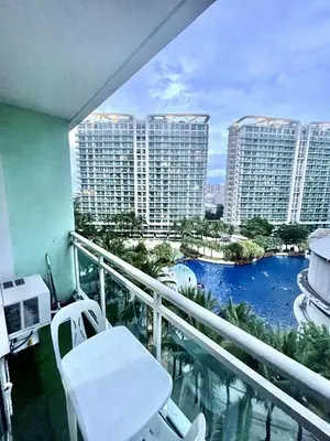 a balcony with a white chair and a view of buildings at AzurestaycationbyGS in Manila