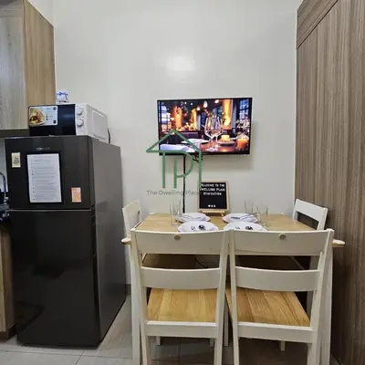 a kitchen with a table with chairs and a television at 1BR Pool View Balcony Near MOA Shore 2 Tower 1 in Manila