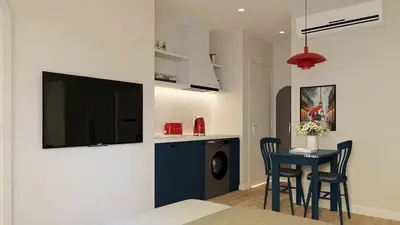 a living room with a table and a tv on a wall at Llanes A Studio Apartment in Manila
