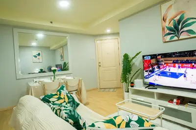 a living room with a couch and a tv at Nature Serenity Suites 2BR Makati in Manila