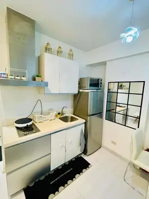 a kitchen with white cabinets and a stainless steel refrigerator at Azure Rio East 221 in Manila