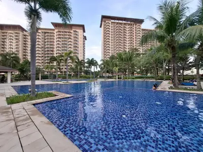 a large swimming pool with palm trees and buildings at Cozy Hotel-Style 1 Bedroom Unit 5L at Eastbay Residences by Rockwell in Manila