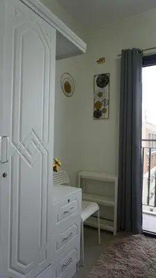a white bedroom with a dresser and a window at Shore 2 Residences in Manila