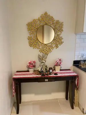 a mirror on a wall above a table with flowers at Apartment in MOA Pasay City Homey Luxury in Manila