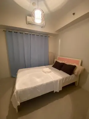 a bedroom with a white bed with a blue curtain at Apartment in MOA Pasay City Homey Luxury in Manila