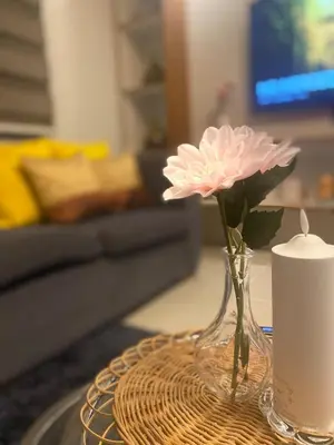 a vase with a pink flower and a candle on a table at Apartment in MOA Pasay City Homey Luxury in Manila
